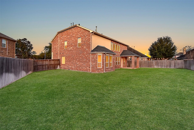 back house at dusk with a lawn