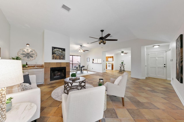 living room with lofted ceiling and a tile fireplace