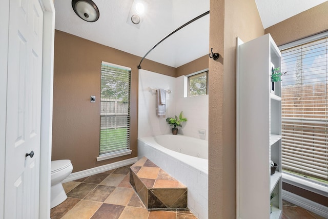 bathroom featuring tiled tub and toilet