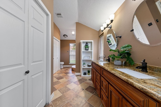 bathroom featuring vanity, toilet, lofted ceiling, and a textured ceiling