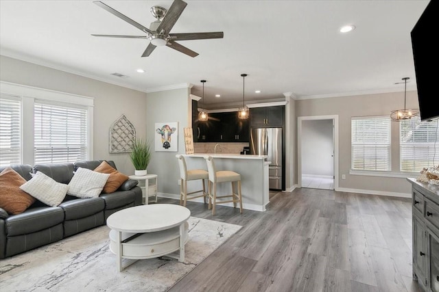 living room with ceiling fan, ornamental molding, a healthy amount of sunlight, and light hardwood / wood-style floors