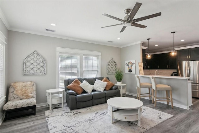 living room featuring crown molding, hardwood / wood-style floors, and ceiling fan