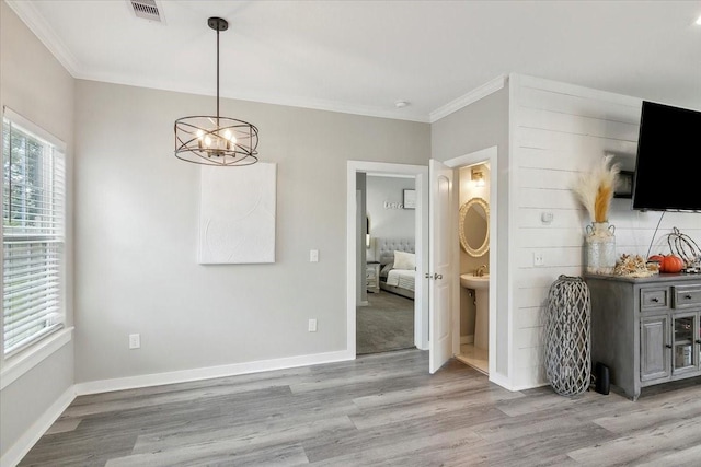 unfurnished dining area with a chandelier, light hardwood / wood-style floors, and ornamental molding