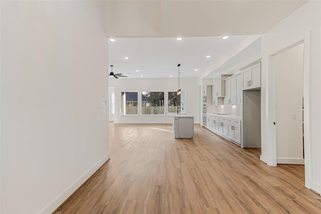 kitchen with sink, a center island, light hardwood / wood-style flooring, pendant lighting, and white cabinets