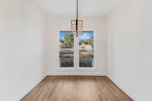 unfurnished dining area featuring light hardwood / wood-style floors and a notable chandelier