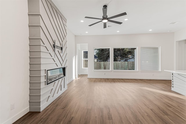 unfurnished living room featuring hardwood / wood-style flooring, ceiling fan, and a fireplace