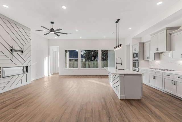 kitchen with a center island with sink, hardwood / wood-style floors, and appliances with stainless steel finishes