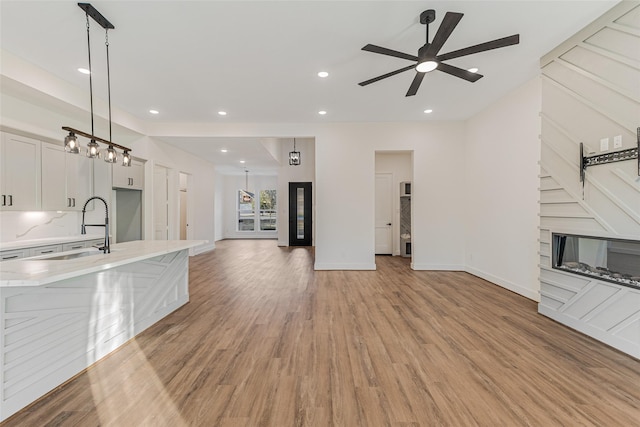 kitchen featuring decorative light fixtures, light hardwood / wood-style floors, white cabinetry, and sink