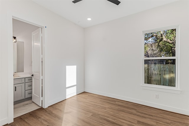 unfurnished bedroom with ensuite bathroom, sink, ceiling fan, and light hardwood / wood-style floors