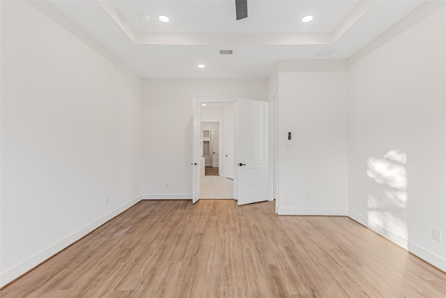 unfurnished room featuring a raised ceiling and light hardwood / wood-style flooring