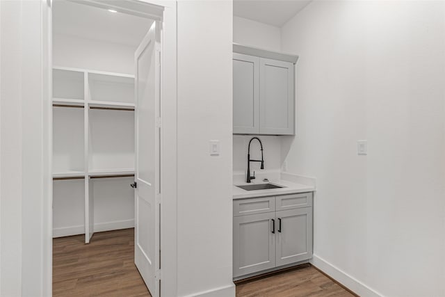 bar featuring gray cabinetry, sink, and light wood-type flooring