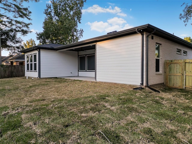 back of house featuring a lawn and a patio