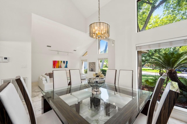 dining room with a chandelier, track lighting, and high vaulted ceiling