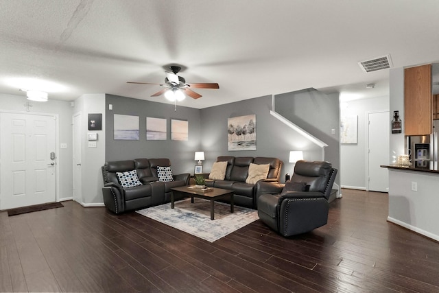 living room with a textured ceiling, ceiling fan, and dark hardwood / wood-style floors