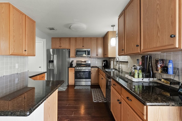 kitchen with dark wood-style flooring, backsplash, stainless steel appliances, and a sink