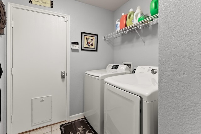 washroom with laundry area, light tile patterned floors, separate washer and dryer, and a textured wall