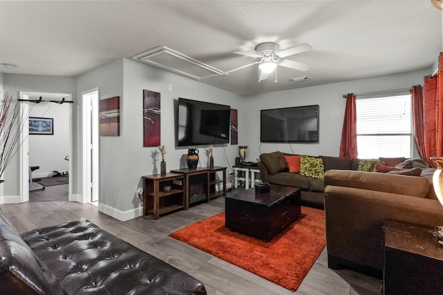 living area with a ceiling fan, wood finished floors, baseboards, visible vents, and attic access