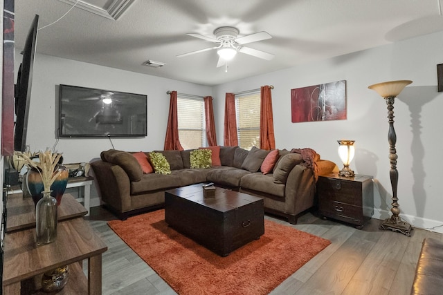 living room featuring baseboards, wood finished floors, visible vents, and ceiling fan