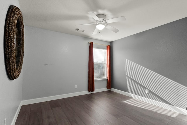 spare room with ceiling fan, visible vents, baseboards, and wood finished floors