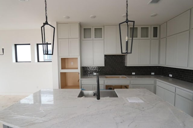 kitchen with sink, white cabinets, light stone countertops, and pendant lighting