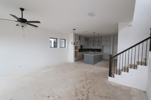 unfurnished living room featuring ceiling fan and sink