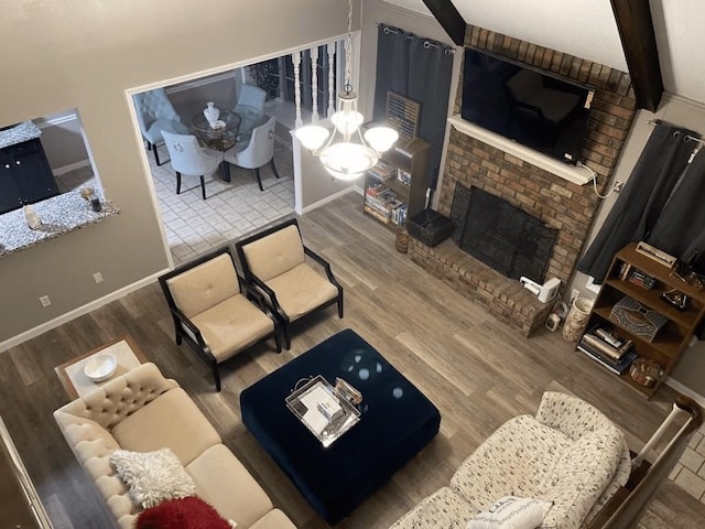 living room featuring a fireplace, beamed ceiling, an inviting chandelier, and hardwood / wood-style flooring