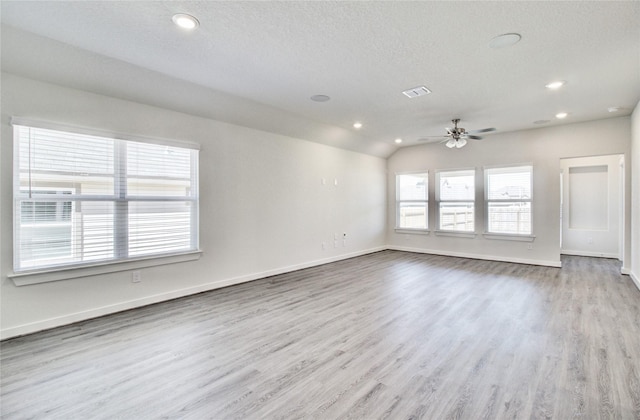 empty room featuring a textured ceiling, ceiling fan, lofted ceiling, and light wood-type flooring