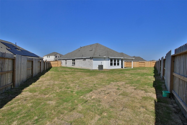 rear view of property with a yard and a fenced backyard
