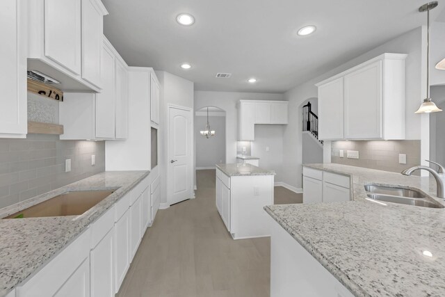 kitchen featuring decorative light fixtures, white cabinetry, and sink