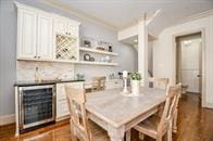 dining area featuring dark hardwood / wood-style flooring, wine cooler, bar, and crown molding