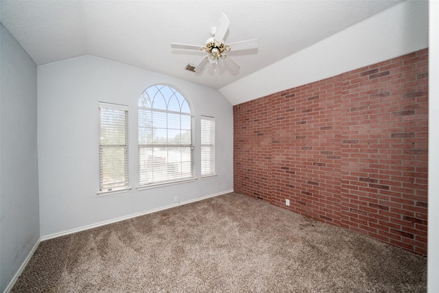 carpeted spare room featuring vaulted ceiling, brick wall, and ceiling fan