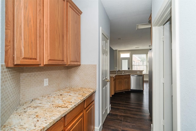 kitchen featuring sink, tasteful backsplash, light stone counters, dark hardwood / wood-style flooring, and dishwasher