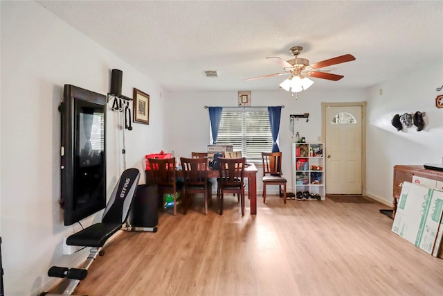 dining room with a textured ceiling, light wood-type flooring, and ceiling fan