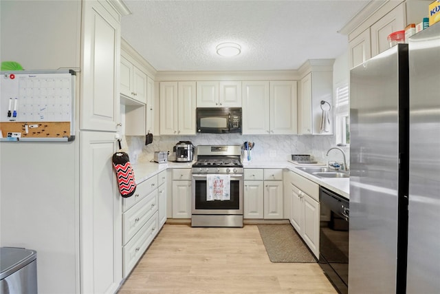 kitchen featuring backsplash, black appliances, sink, light hardwood / wood-style flooring, and a textured ceiling