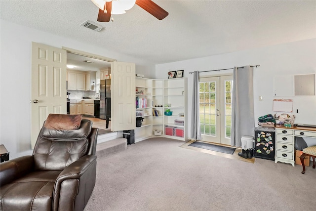 carpeted living room featuring a textured ceiling and ceiling fan