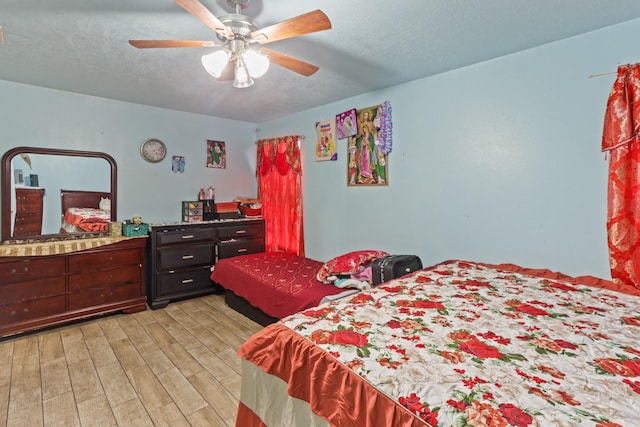 bedroom with ceiling fan, light wood-type flooring, and a textured ceiling