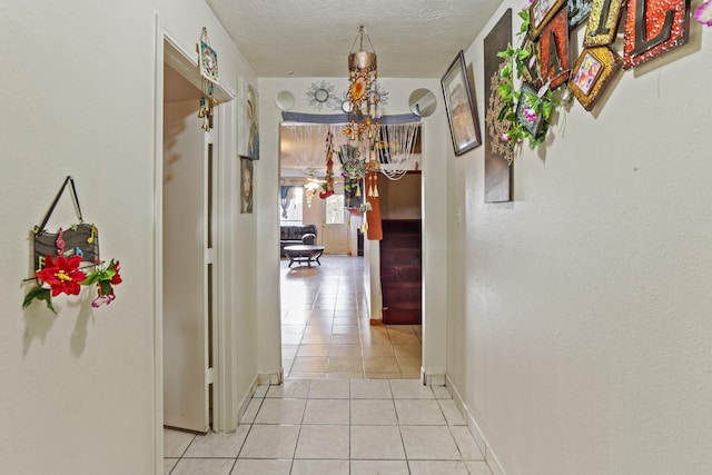 corridor featuring light tile patterned floors and a textured ceiling