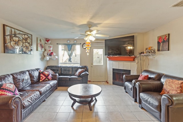 living room featuring a tile fireplace, ceiling fan, and light tile patterned floors