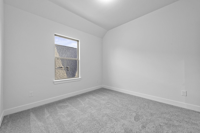 carpeted spare room with vaulted ceiling