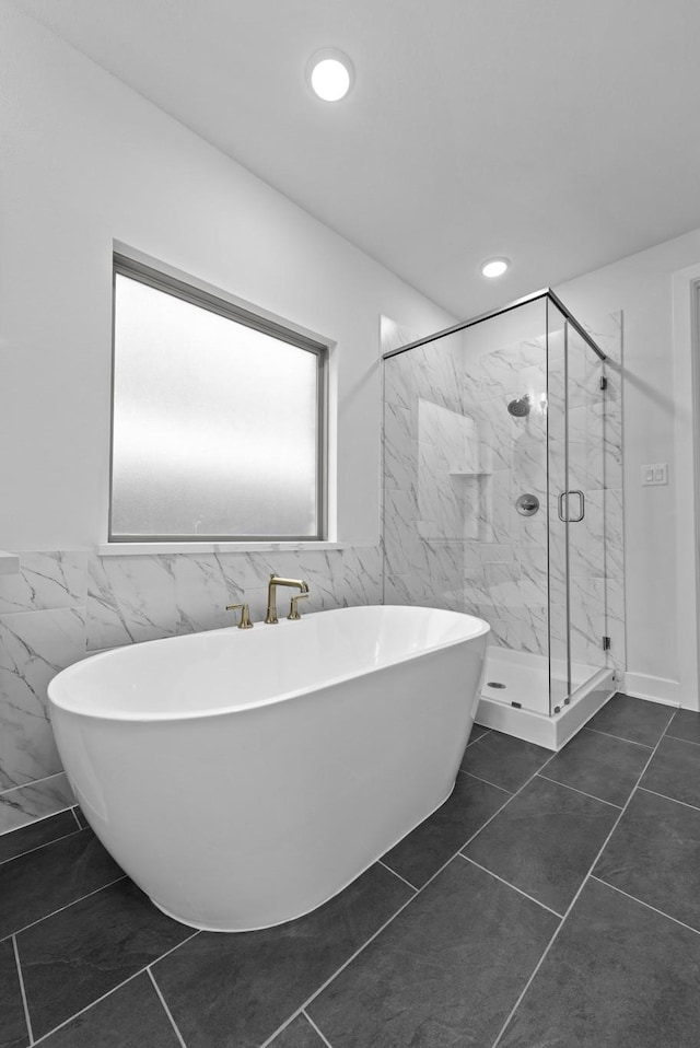 bathroom with tile patterned floors, tile walls, and plus walk in shower