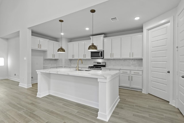 kitchen featuring a center island with sink, white cabinets, stainless steel appliances, and sink