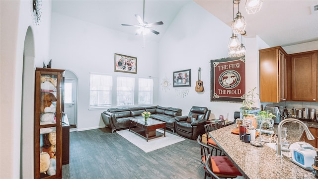 living room featuring ceiling fan, high vaulted ceiling, and dark wood-type flooring