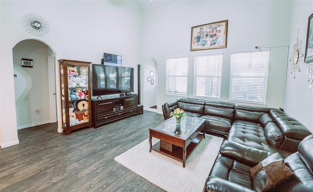 living room featuring a towering ceiling and dark wood-type flooring