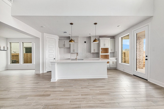 kitchen with a wealth of natural light, a center island with sink, hanging light fixtures, and sink