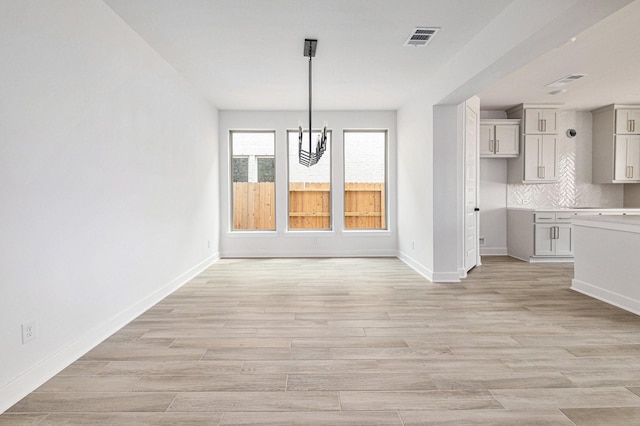 unfurnished dining area featuring light hardwood / wood-style floors and a chandelier