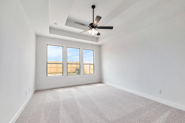 carpeted empty room with a tray ceiling and ceiling fan