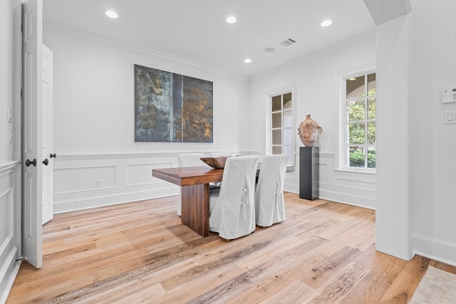 dining space with ornamental molding and light hardwood / wood-style flooring