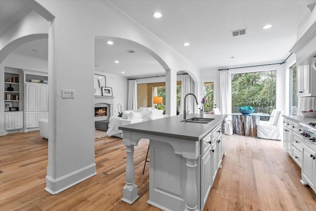 kitchen with sink, light hardwood / wood-style flooring, an island with sink, a kitchen bar, and white cabinetry