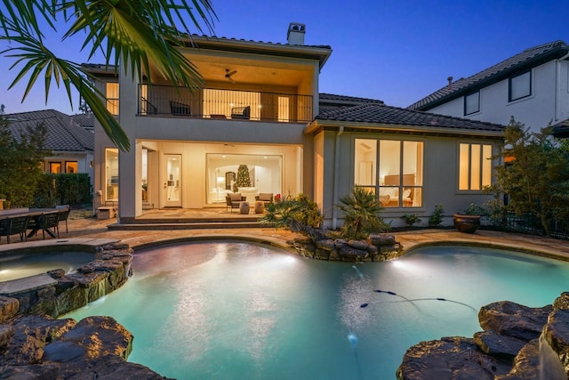 rear view of property with a swimming pool with hot tub, a patio, a balcony, and ceiling fan