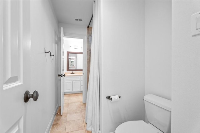 bathroom with toilet, vanity, and tile patterned floors